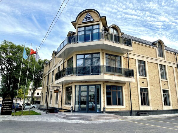 A hotel with a modern architectural design, featuring a prominent sign at the top, large windows, and a balcony. - Alpha Plaza (Tashkent)