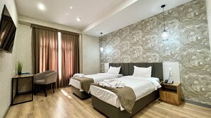 A modern hotel room with two beds, a desk, a chair, and a TV. - Alpha Plaza (Tashkent)
