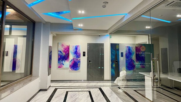 A modern lobby with a glass wall, abstract art, and a marble floor. - Alpha Plaza (Tashkent)