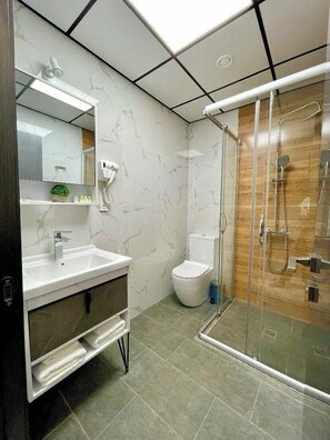 A modern bathroom with a glass-enclosed shower, a white sink with a mirror, and a toilet. - Alpha Plaza (Tashkent)