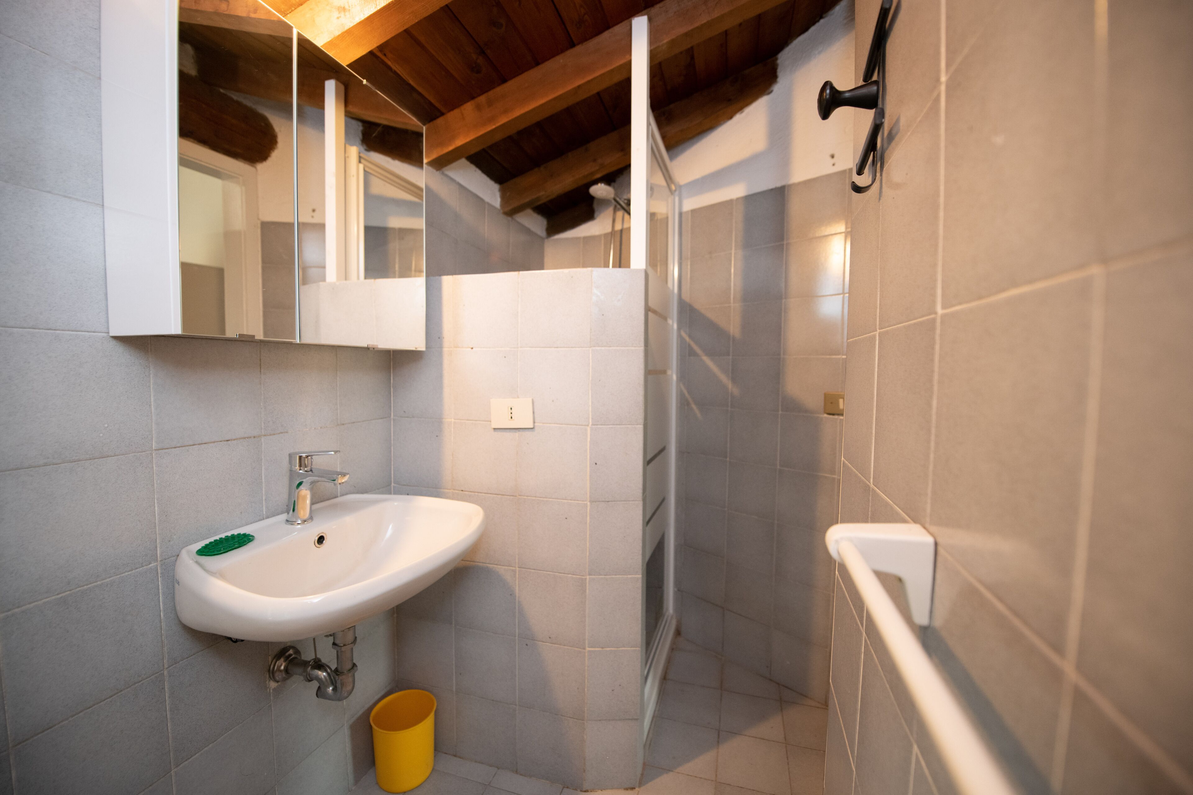 Une salle de bain avec un lavabo blanc, un miroir et des murs carrelés.