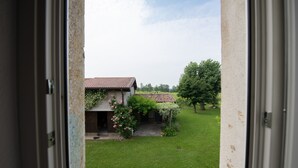 Vista desde una ventana que da a una casa con techo de tejas, un jardín y un árbol.