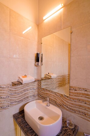 A bathroom with a sink, mirror, towel rack, and patterned wall tiles. - hotel Mehrangarh Palace (Udaipur)