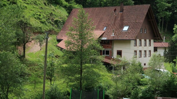 A house with a red-tiled roof, surrounded by lush greenery and a trampoline in the yard. - Wonderful private villa for 18 people with WIFI, TV, terrace and pets allowed (Nonnenbach)