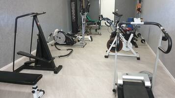 Ein Fitnessstudio mit verschiedenen Trainingsgeräten, darunter Laufbänder, Ergometer und Kraftgeräte.