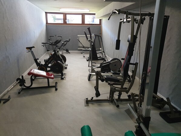 Ein Fitnessraum mit Trainingsgeräten, darunter Laufbänder, ein Ergometer und Kraftgeräte.