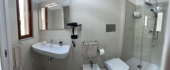 A modern bathroom with a sink, mirror, towel rack, toilet, and shower.