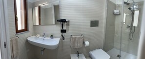 Une salle de bain moderne équipée d’un lavabo, d’un miroir, d’un porte-serviettes, de toilettes et d’une douche.