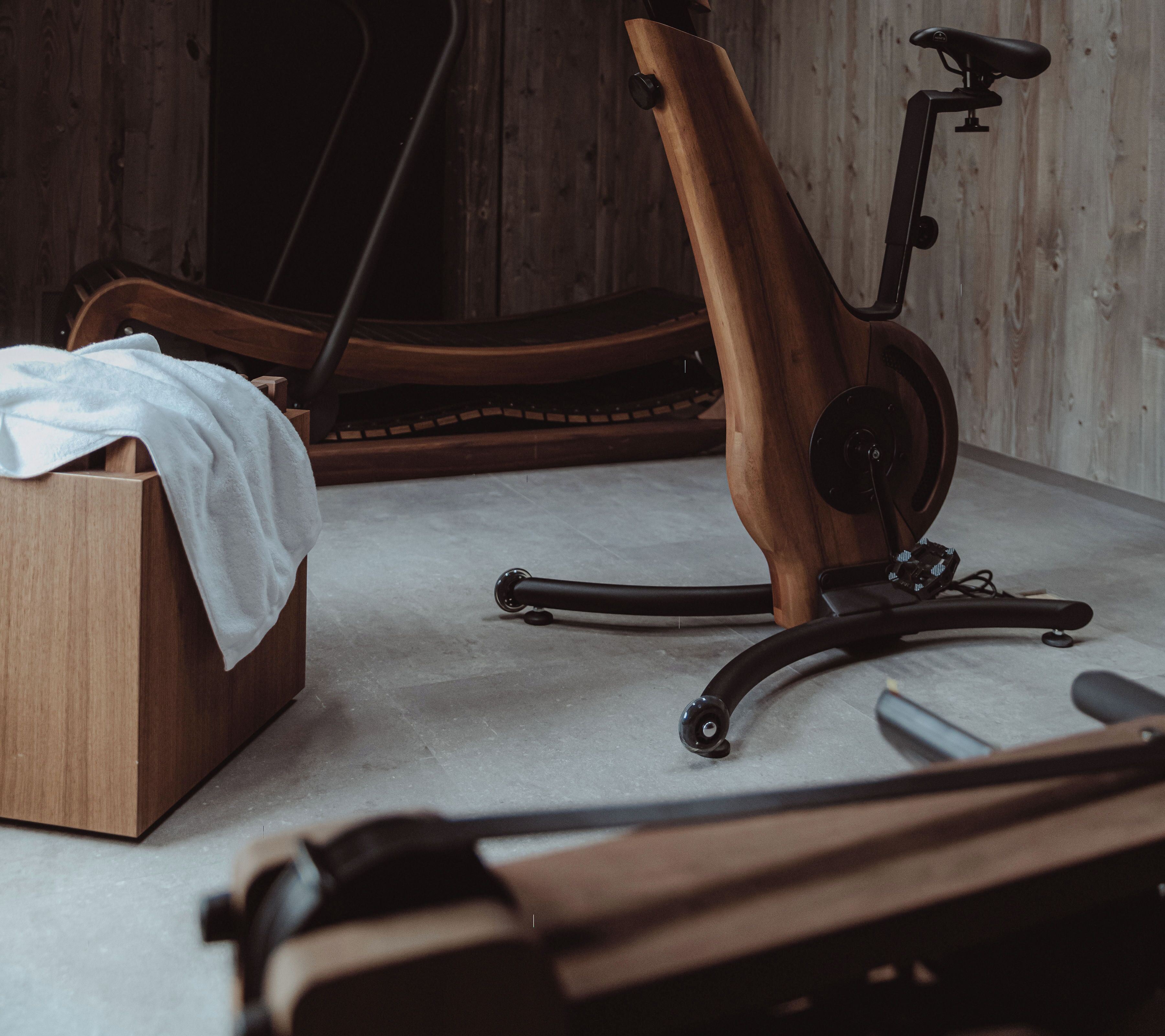 Een stilstaande hometrainer, een houten doos en een handdoek op een betegelde vloer.