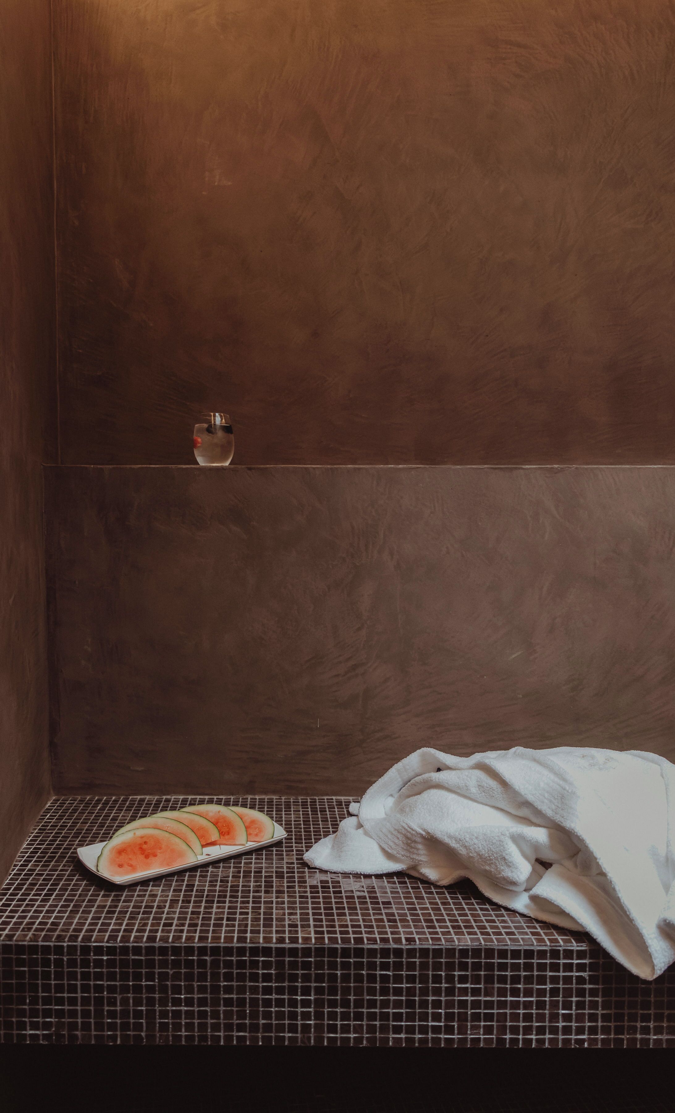 A bathroom with a tiled floor, a white towel, and a plate of watermelon slices.