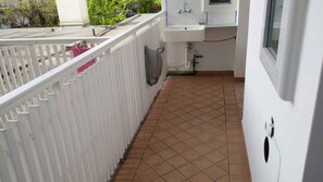 A narrow corridor with a tiled floor, a white railing, and a window on the right.