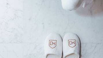A pair of white slippers with a logo on a white tiled floor.