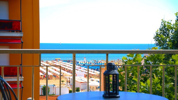 Un balcon donnant sur une plage, une table avec une lanterne et une rambarde.