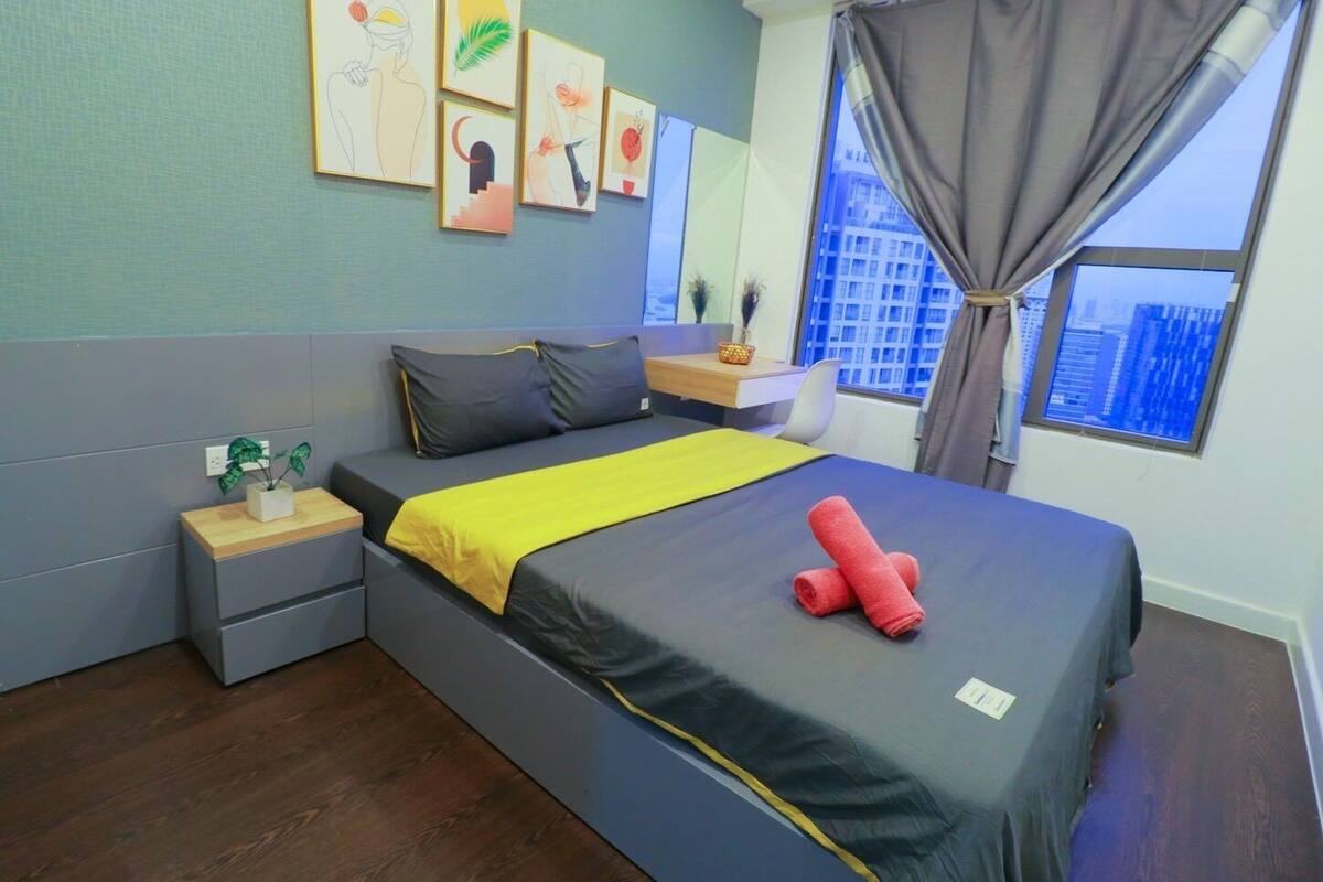 Ein modernes Schlafzimmer mit Bett, Nachttischen, Schreibtisch und Kunstwerken an der Wand.