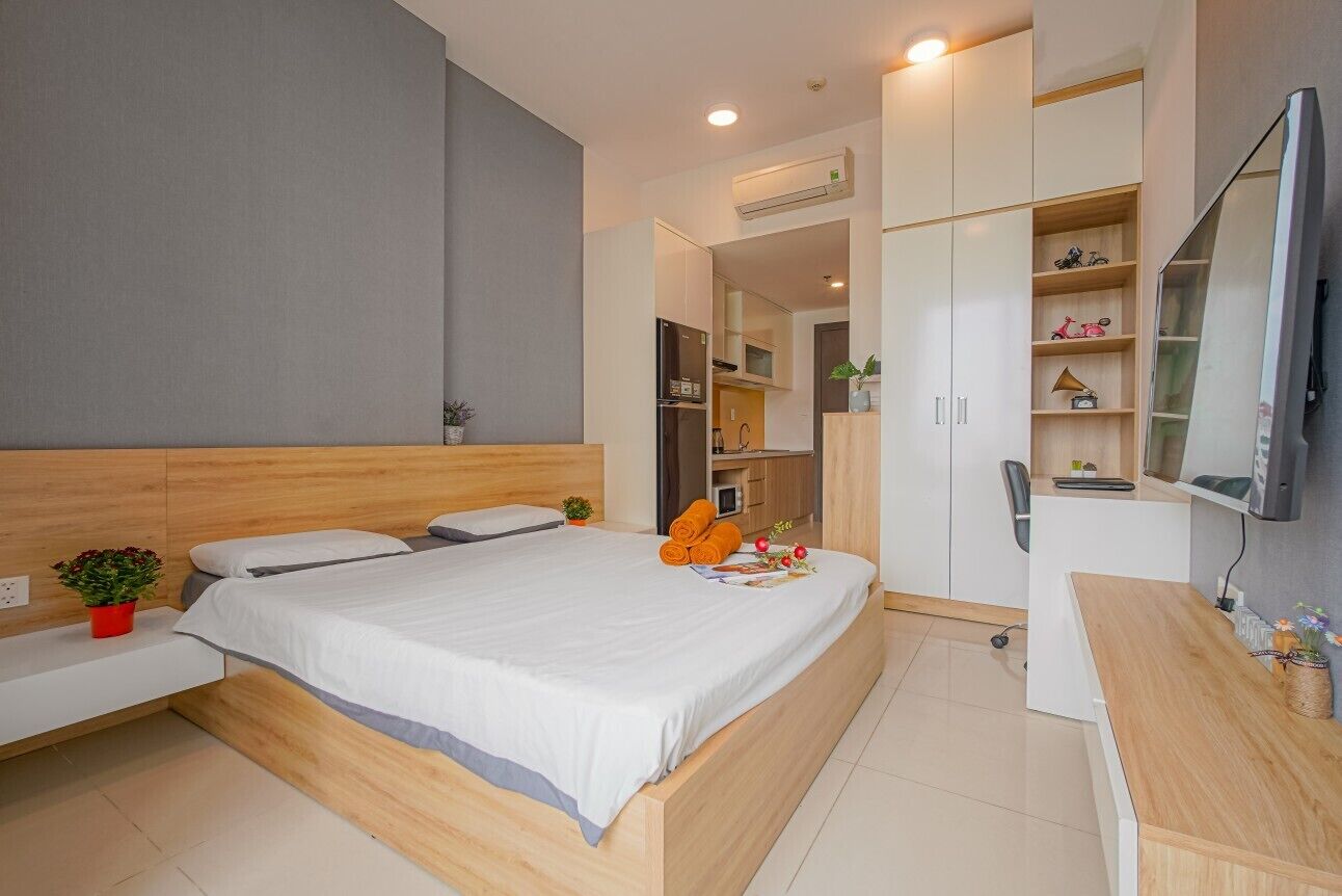A modern bedroom with a large bed, a desk, and built-in storage.