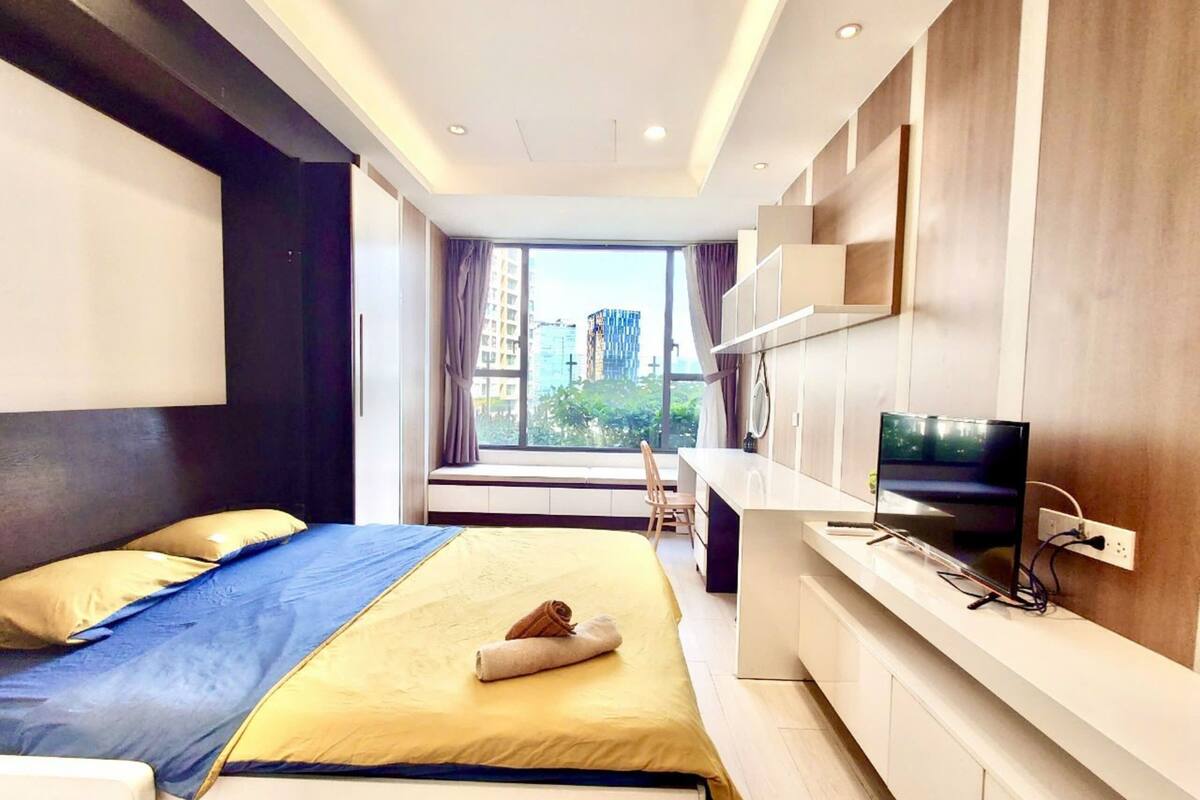 Ein modernes Hotelzimmer mit einem Bett, einem Schreibtisch mit Fernseher und einem großen Fenster mit Blick auf die Stadt.