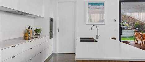 A modern kitchen with white cabinetry, a built-in oven, and a large island with a sink.