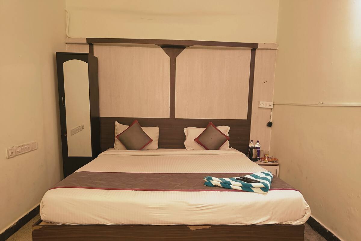 Een netjes opgemaakt bed met een houten hoofdbord, twee kussens en een deken.