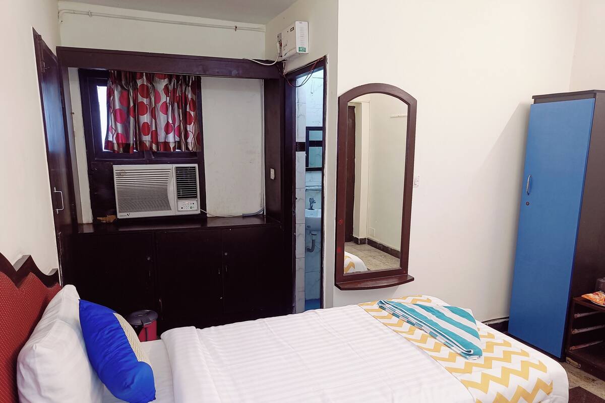 Een hotelkamer met een bed, een kledingkast, een spiegel en een airconditioning.