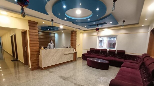 Um saguão de hotel com balcão de recepção, área de estar e design de teto moderno.