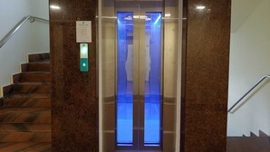 Um elevador com visor digital, um corredor de escadas com corrimão e uma placa indicando 'Dynamic Lifts'.