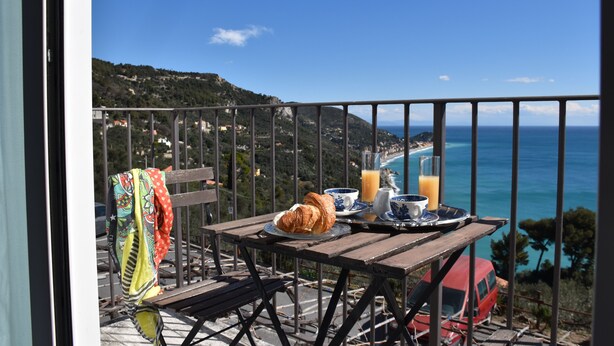 A balcony with a table set for breakfast, overlooking a coastal view. - La Gioiosa (Finale Ligure)