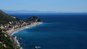 A coastal town with a beach, buildings, and mountains in the background. - La Gioiosa (Finale Ligure)