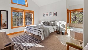 A bedroom with a bed, a desk, a chair, a window, a ceiling fan, and a view of trees. - Broken Arrow Abode (Overgaard)