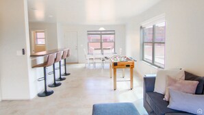 A spacious living area with a foosball table, a bar with stools, and a sofa with cushions. - Moab Mirage Hot Tub and Pool (Moab)