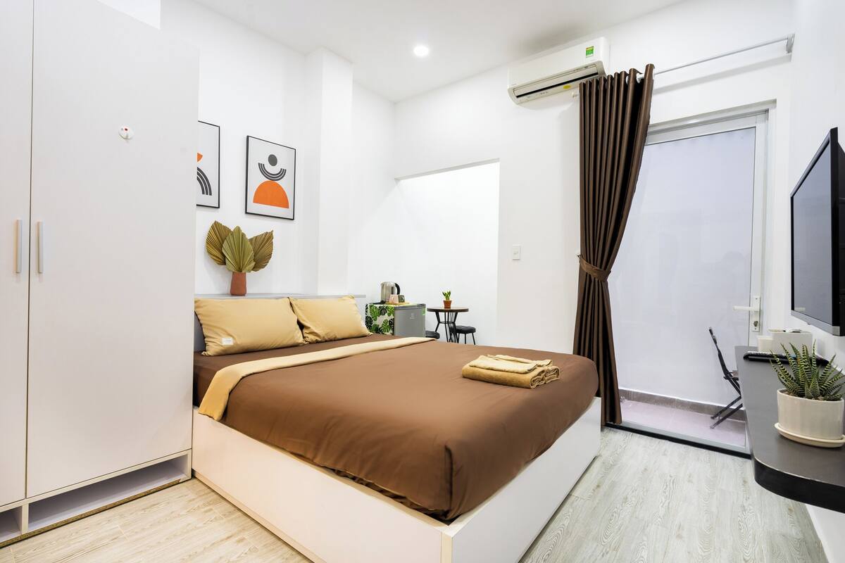 Ein modernes Hotelzimmer mit Bett, Schreibtisch, Stuhl, einem Blumentopf und einem Fernseher.