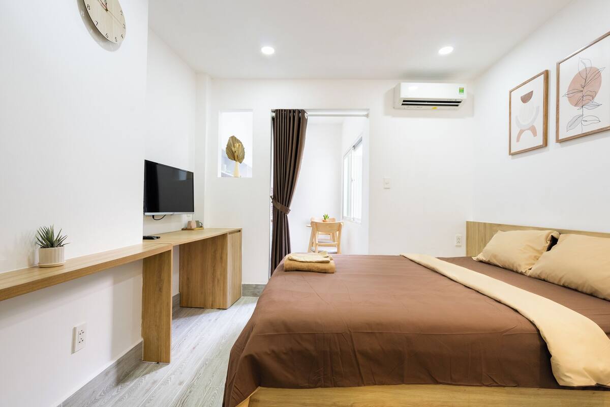 Ein modernes Schlafzimmer mit Bett, Schreibtisch, Fernseher und einem Fenster mit Vorhängen.