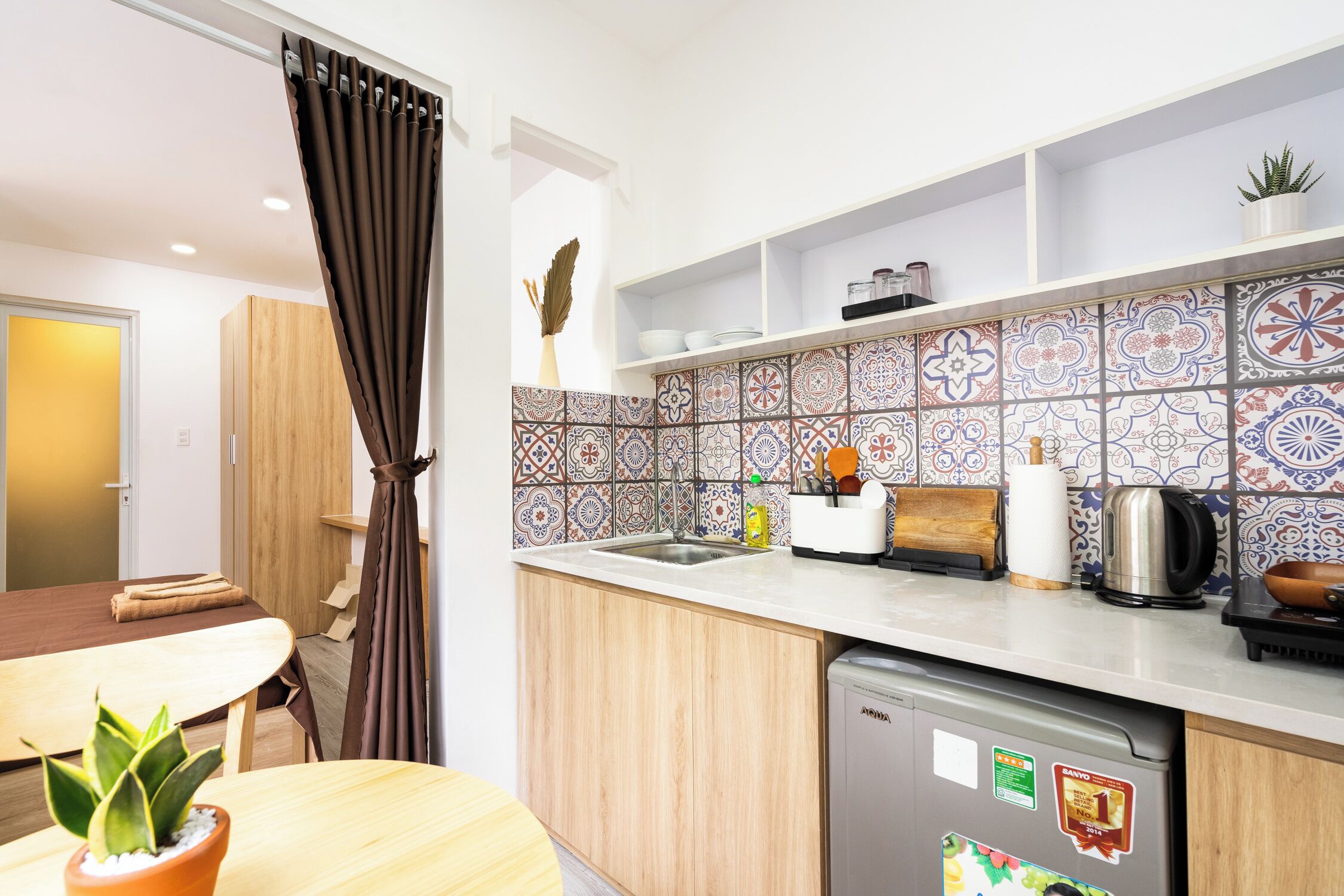 Una cucina compatta con lavastoviglie, lavello e piano di lavoro con diversi utensili da cucina.