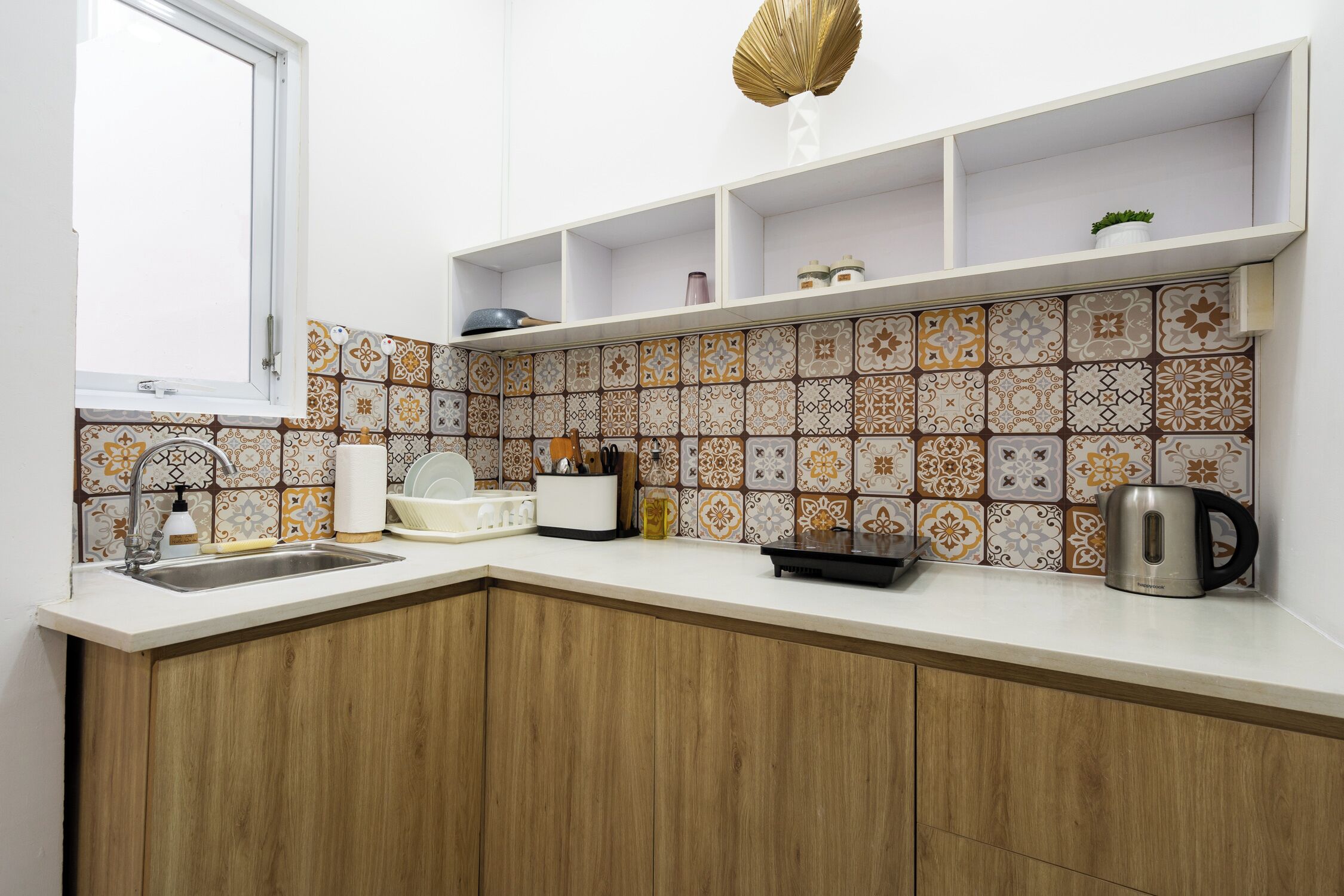 A kitchen with a white countertop, wooden cabinets, a sink, and a backsplash with patterned tiles.
