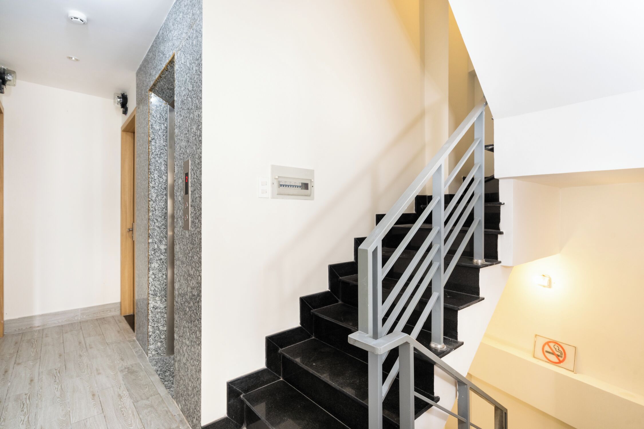 Een modern interieur met een trap, een marmeren wand en een lichtschakelaar.