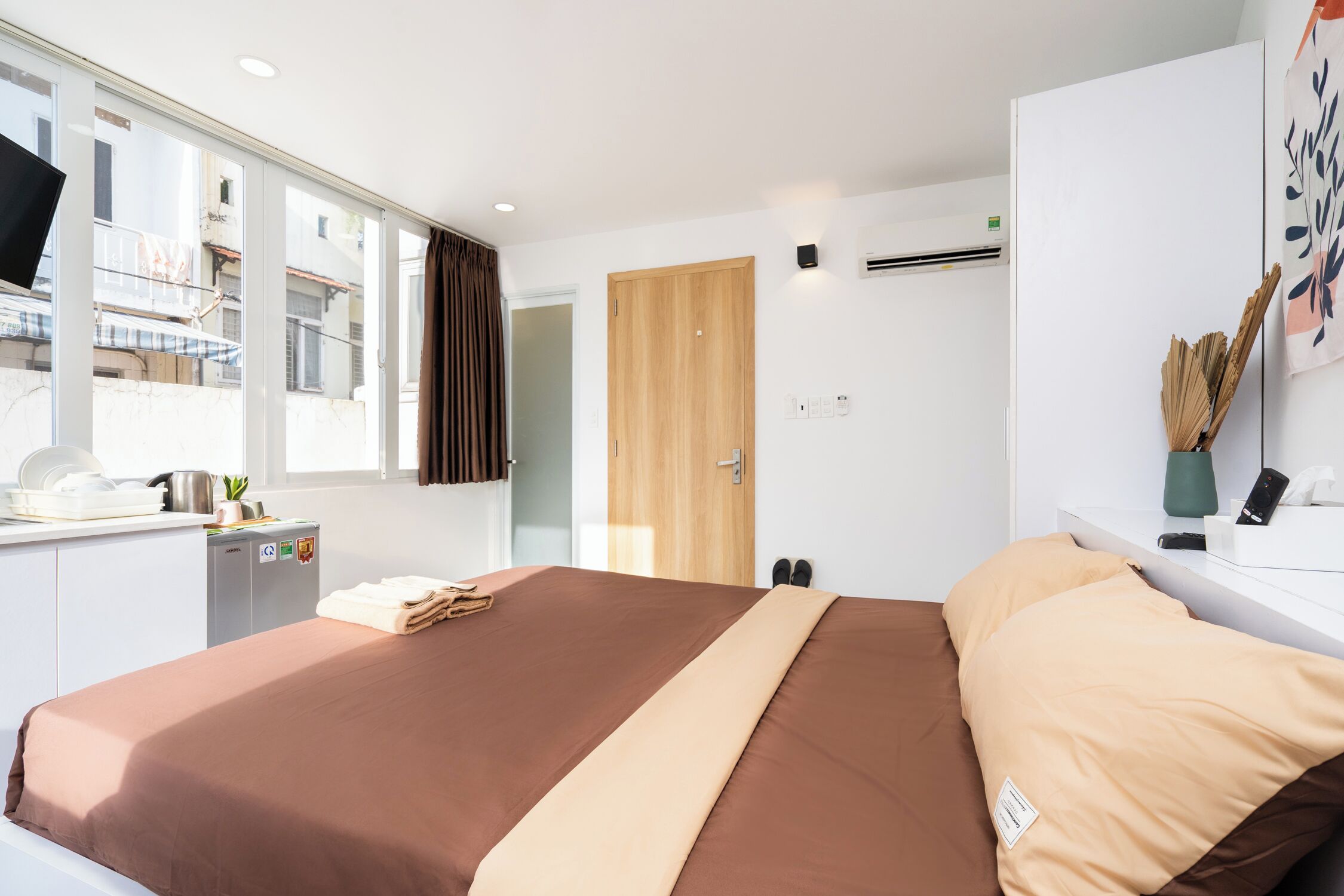 Une chambre d’hôtel moderne dotée d’un grand lit, d’un bureau avec un ordinateur, d’une fenêtre avec des rideaux et offrant une vue sur l’extérieur.