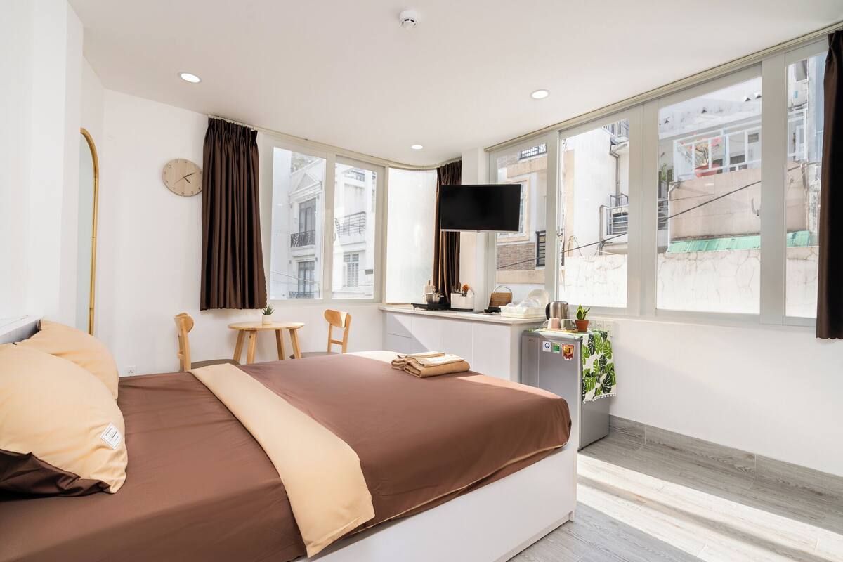 Ein modernes Hotelzimmer mit einem großen Bett, einem Schreibtisch, einem Fernseher und einem Fenster mit Blick auf die Stadt.