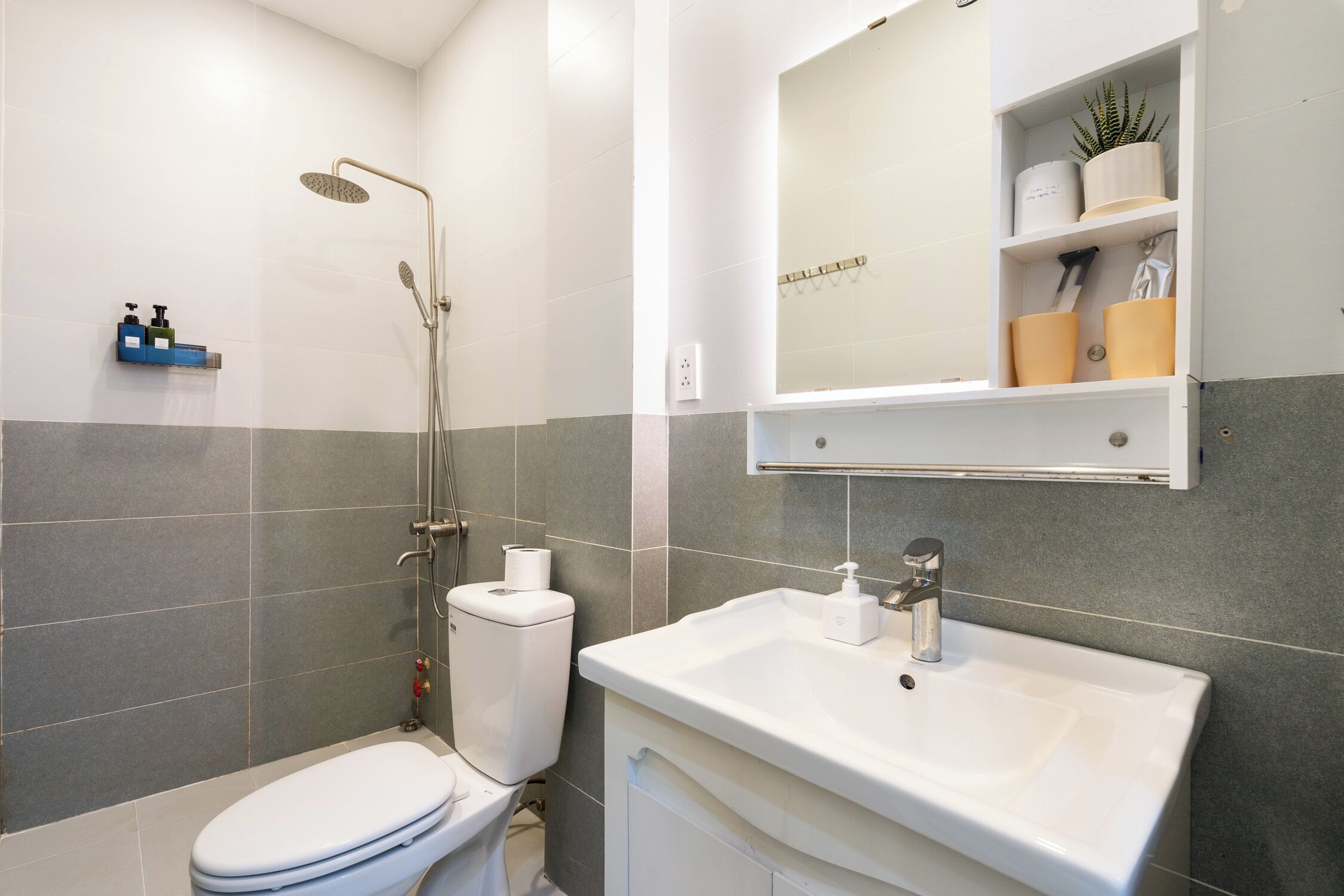 Een moderne badkamer met toilet, douche en wastafel.