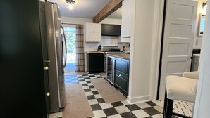 A kitchen with a black and white checkered floor, a refrigerator, cabinets, and a sink. - Litchfield Modern Farmhouse (Litchfield)