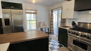 A kitchen with a central island, a stainless steel refrigerator, a stove, and a checkered floor. - Litchfield Modern Farmhouse (Litchfield)