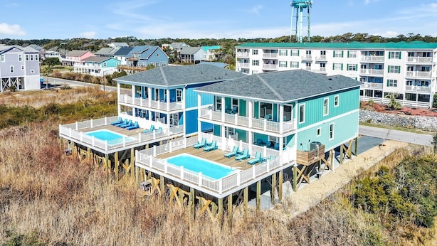 A two-story beachfront property with a pool on the first floor and a balcony on the second floor. - Oceanview Dog Friendly Home with Heated Pool and Golf Cart, 7 Green Pelicans (Oak Island)