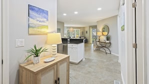 A modern kitchen with white cabinets, a wooden countertop, and a potted plant.