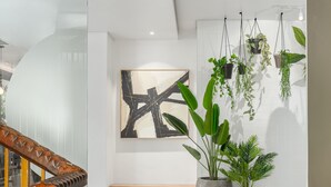 Un interior moderno con una escalera, un banco de madera y plantas en macetas.