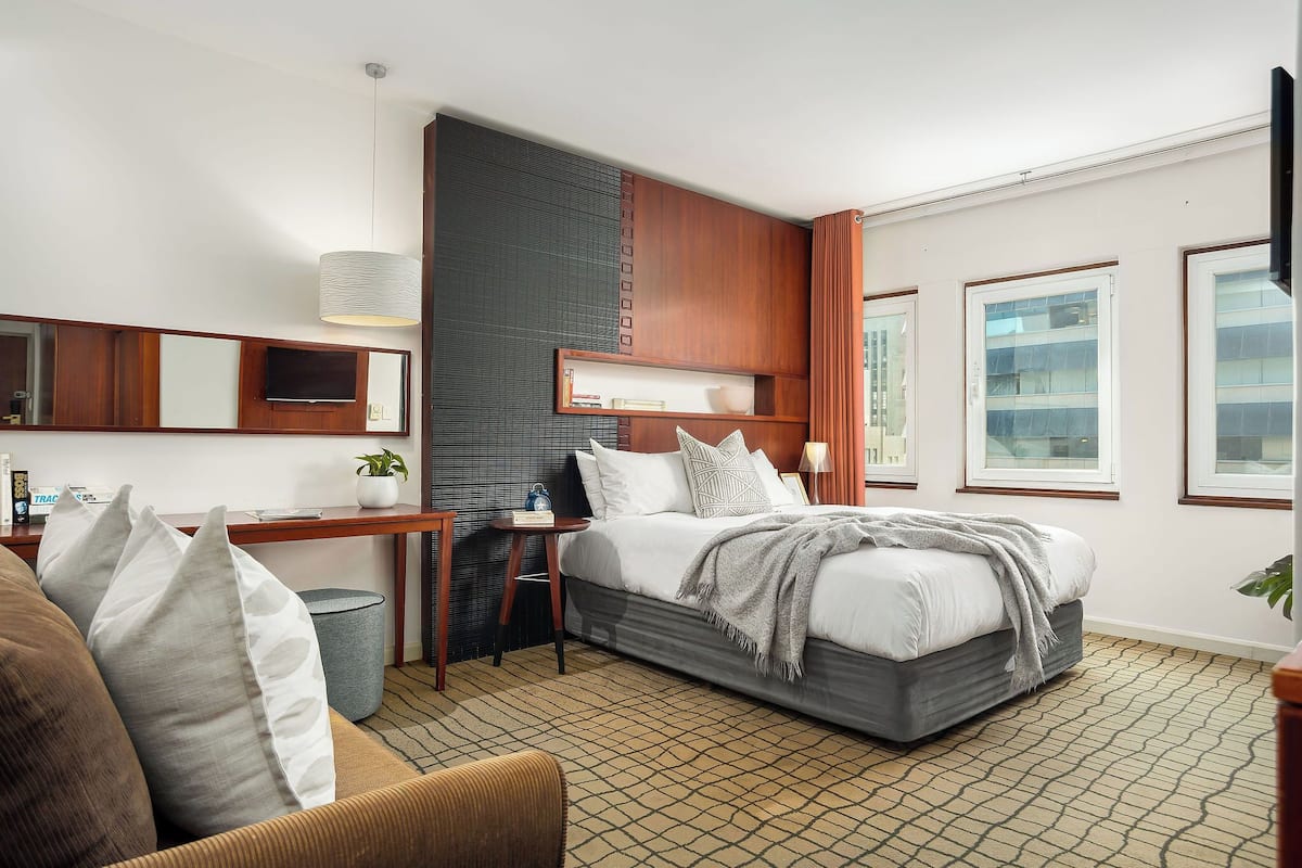 Una habitación de hotel moderna con una cama grande, un escritorio, una silla y una mesita.