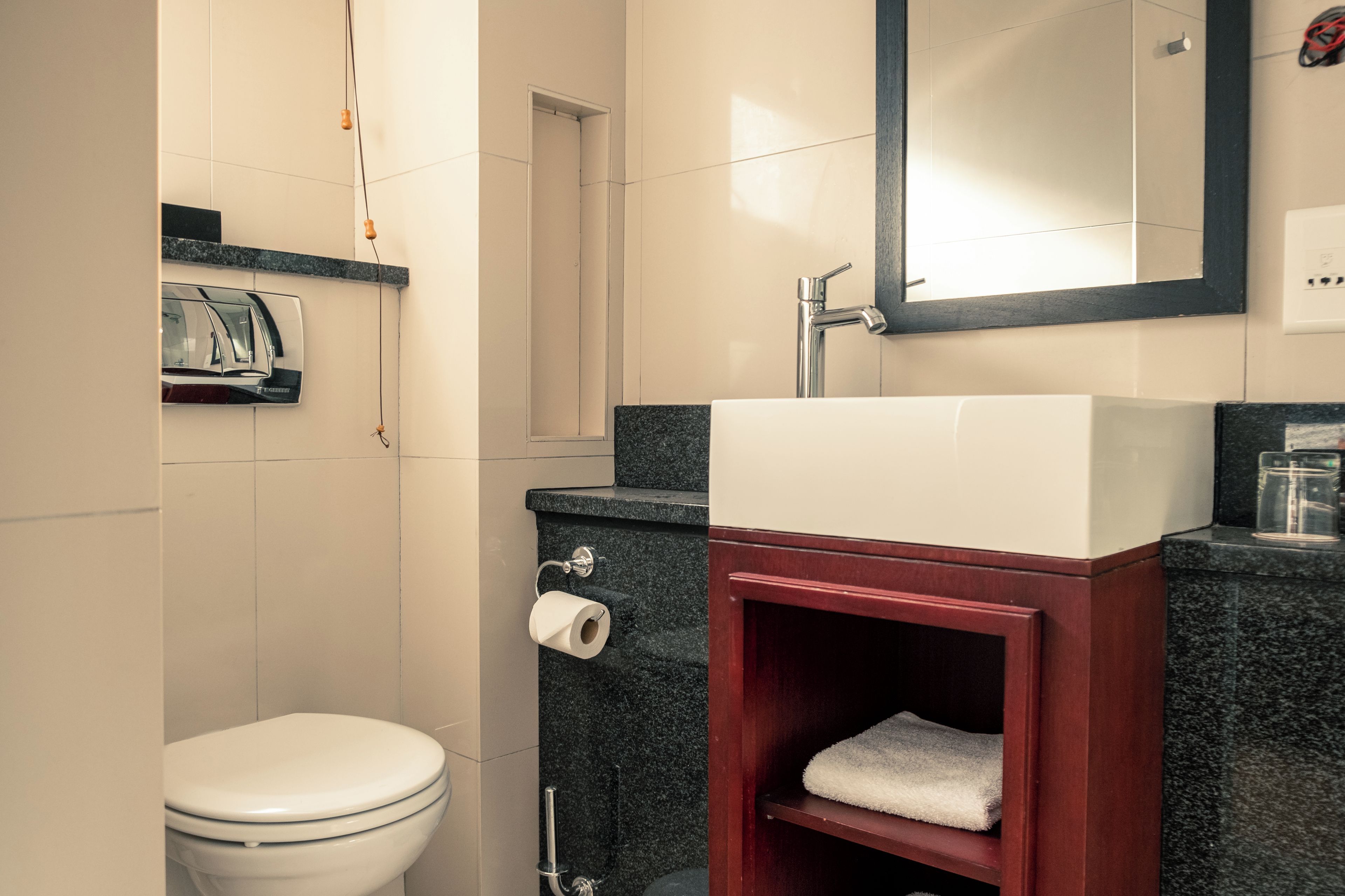 A bathroom with a toilet, a sink, a mirror, and a towel rack.