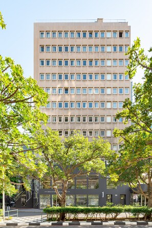 A multi-story building with a uniform facade, numerous windows, and a visible entrance with a staircase. - Neighbourgood East City (Cape Town)
