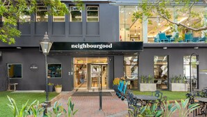 Un edificio moderno con un letrero que dice 'neighbourhood', asientos al aire libre y macetas.