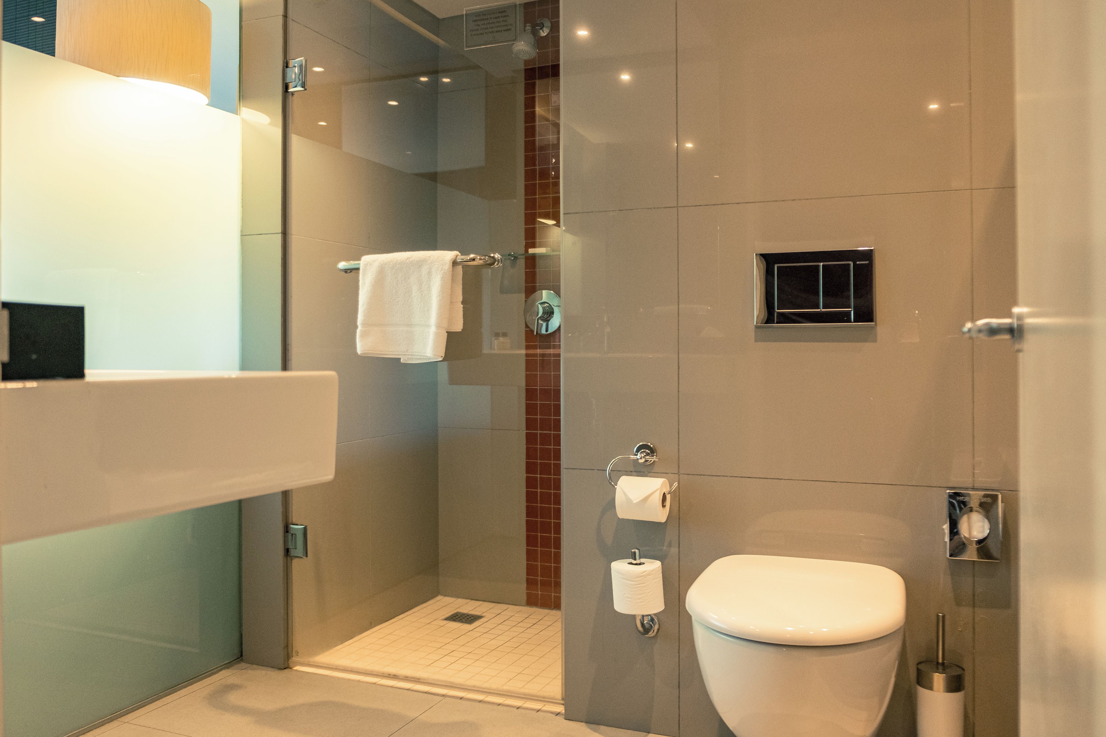 A modern bathroom with a glass-enclosed shower, a white toilet, and a towel rack.
