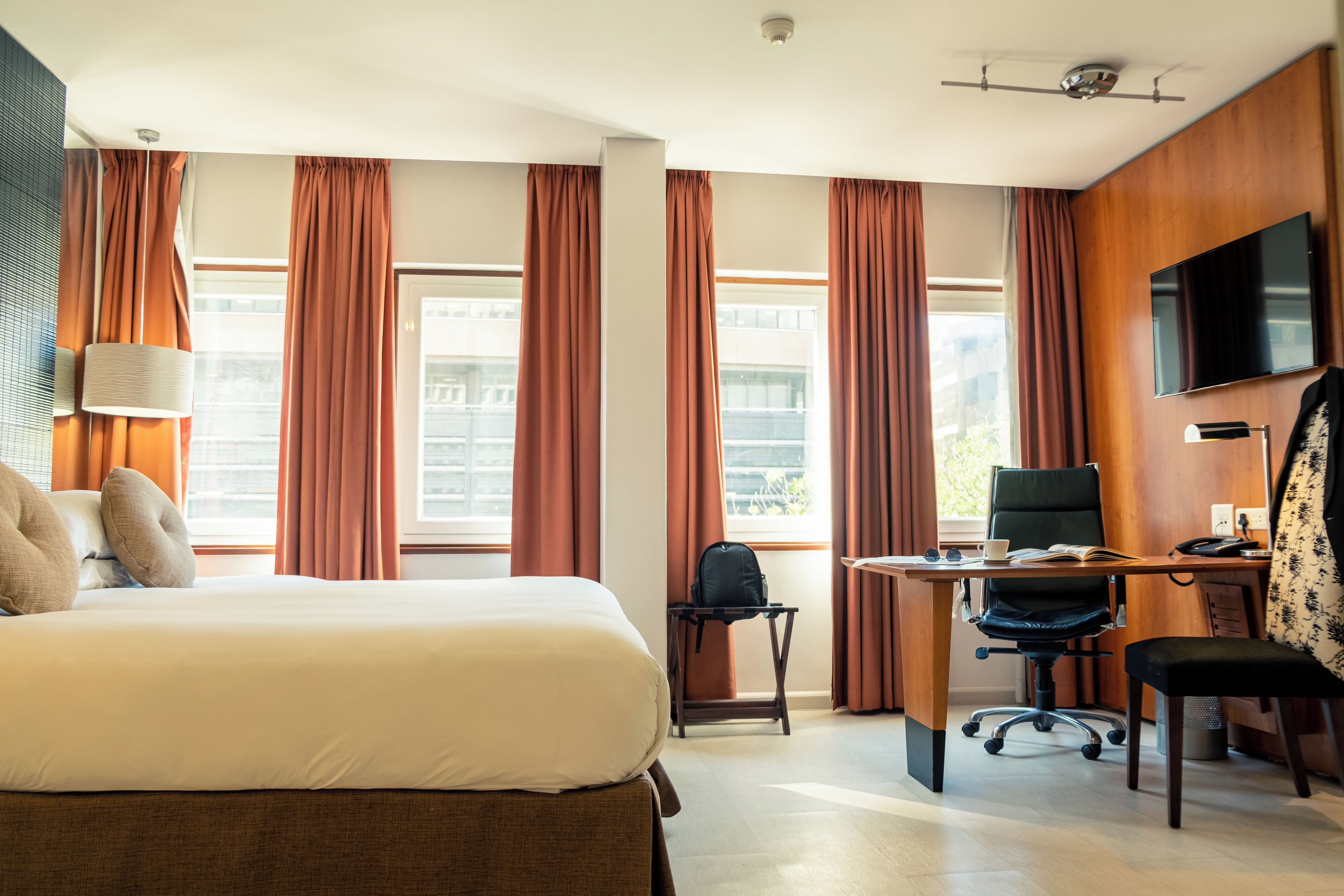 Een hotelkamer met een bed, bureau, stoelen en een televisie.