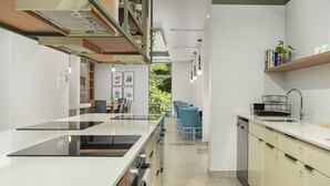 Una cocina moderna con una isla central, electrodomésticos integrados y un comedor con sillas azules.