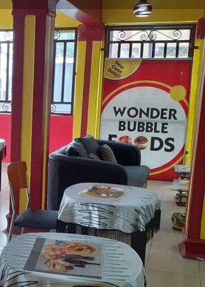 A restaurant interior with a 'Wonder Bubble Foods' sign, a sofa, and tables with menus.